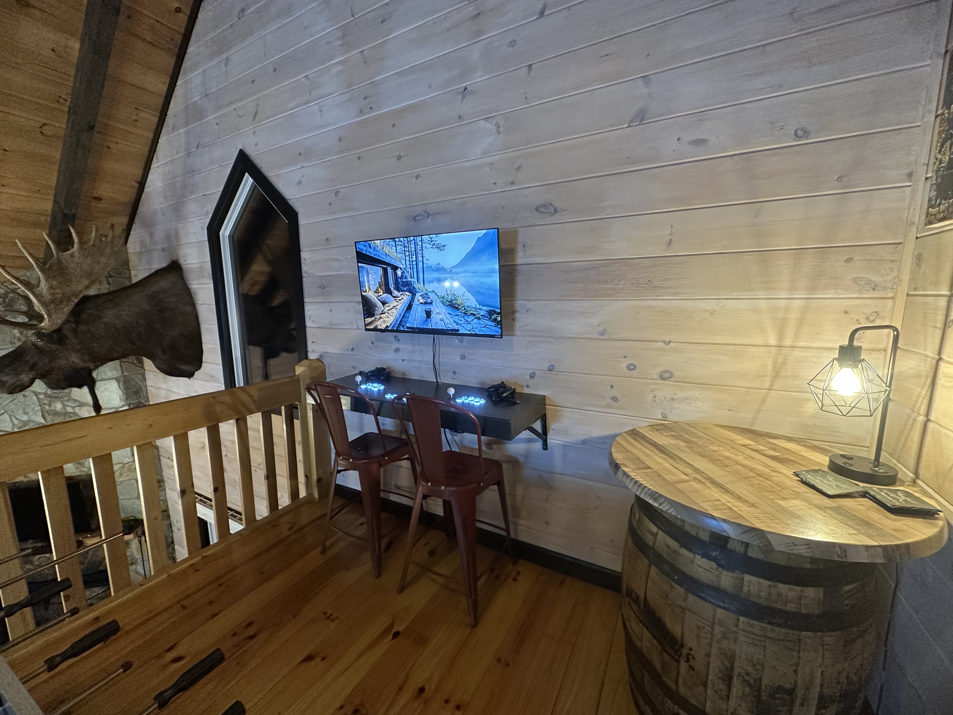 A loft detail with the arcade, TV, barrel table, and Moose keeping watch.